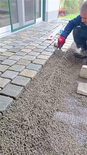 Worker Installing Stone Pavers Over Compacted Gravel Base Layer
