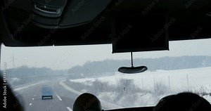 Passenger point of view looking toward front large windshield of a coach bus driving highway left steering wheel