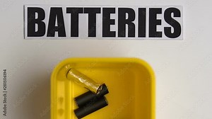 Person putting used battery into plastic container, waste sorting, recycling