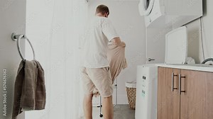 Young man using washing machine at home. A man takes clothes from the washing machine and hang it on dryer. Laundry day Stock Video