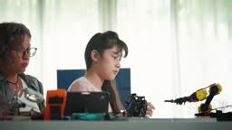 A student in a high-tech classroom operates a robotic arm using a...