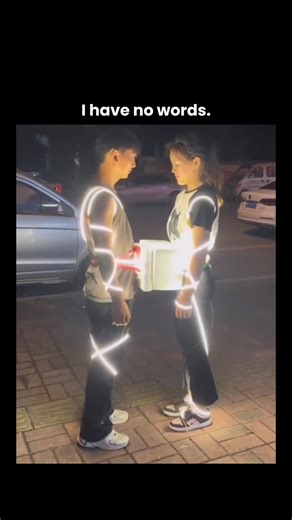 Wild Videos on Instagram: "The video features a short 9-second clip where a man and a woman hug each other while wearing glowing string lights wrapped around their bodies. As they embrace, the lights flicker brighter, making the moment look oddly romantic and dramatic at the same time. Just when it feels wholesome, another man suddenly pours water over the glowing lights. Instantly, a loud shock sound effect plays, flipping the entire mood from sweet to chaotic comedy in a split second. The exag