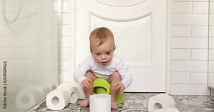 Funny baby boy sitting on chamberpot, Children's legs hanging down from a chamber-pot. Kid plays toilet paper