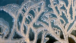 Close-up of frost patterns forming on a windowpane, creating intricate designs.