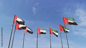 National symbol of United Arab Emirates flags in blue sky background. Seven UAE flags represent seven emirates waving in wind.