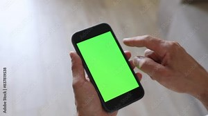A man is holding a phone with a green screen. Using chromakey on your phone screen. Place for text, pictures. Business, finance, training.