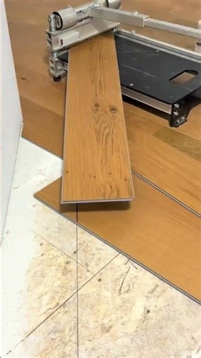 cutting the long brown wood laminate flooring planks using a precise flooring cutter machine at home
