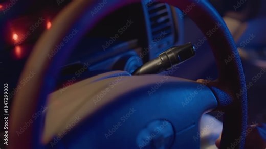 Driver toggles steering and signals attentively, Closeup of driver adjusting controls with dashboard illumination, Instructor in vehicle readying for ride as dashboard lights flicker softly