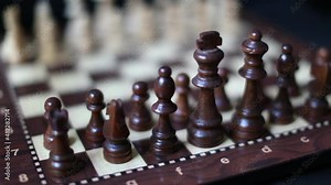 wooden black chess pieces on the board. blurry and black background. The chessboard is turning.
