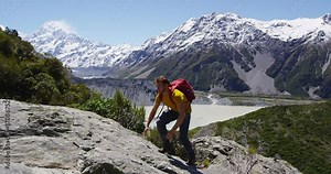 Hiker hiking scrambling on adventure climbing up mountain on hike in amazing nature landscape. Man tramping and trekking by view of Mt Cook in Aoraki / Mount Cook National Park. RED EPIC.
