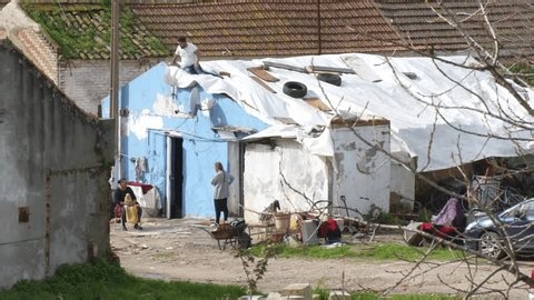 clip-3998841979-gypsy-man-repairing-house-roof-white-tarp
