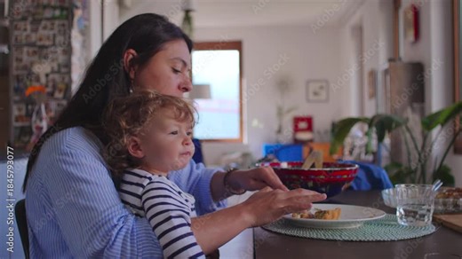 Mother eating at table with toddler on lap creating warm moment of shared mealtime closeness comfort and everyday routine in bright family home environment