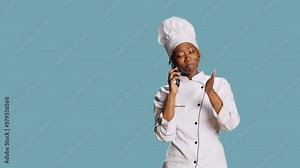 Professional chef talking on phone call in studio, having remote conversation using smartphone telephone line. Young person working as cook in culinary industry, answering mobile phone.