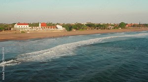 The beaches of Canggu during sunset. With beach clubs, hotels, resorts, restaurants and surfers. Aerial shot.