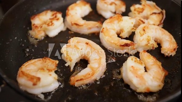 Cooking shrimp in a pan, seafood grill, kitchen preparation, stove heat.