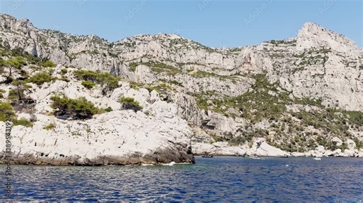 Boat ride view of Calanque de Morgiou bay with turquoise Mediterranean water, limestone cliffs and rocky coastline in Calanques National Park on the French Riviera, France.