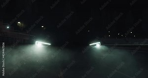 Cinematic close up shot of modern racing car with switched on headlights running on race track at night. Concept of passion for driving cars and engines,auto dealership, luxury cars, speed and power.
