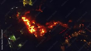 Building fire, Aerial 4k view of firemen fighting a structure in flames, dark smoke rising from a warehouse ruins, during night time, in Port-au-Prince, Haiti - pan, drone shot