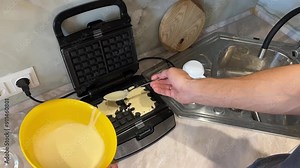 Make delicious homemade waffles by pouring batter into a waffle iron and closing the lid in a modern kitchen. Step by step process for perfect breakfast