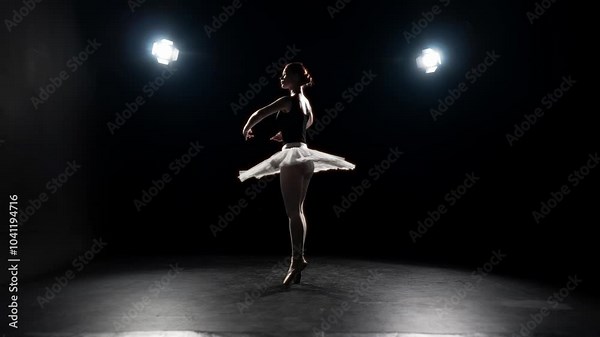 Attractive ballerina in tutu and pointe shoes dancing on stage in night. Beautiful young adult woman rehearsing classical choreography in darkness, elegance and beauty of professional ballet dancer