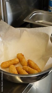 cheese sticks are deep fried. cheese sticks in batter put in the deep fryer. fryer with cheese sticks dipped into boiling oil. potatoes are deep fried