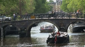 Boat waiting for canal boat passing by at a bridge in Amsterdam