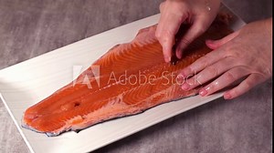 Deboning raw trout fillet. Taking out fish bones with tweezers. Preparing to cook seafood meal