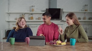 Positive deaf diverse people video conferencing online with digital tablet using sign language in domestic kitchen. Hearing impaired friends with tablet pc chatting online using sign language indoors.