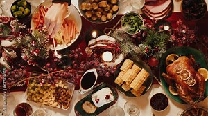 Hand lighting candles on dining table top view. Friends celebrating new year, delicious dishes, cooked homemade food on plates. Christmas party at home.
