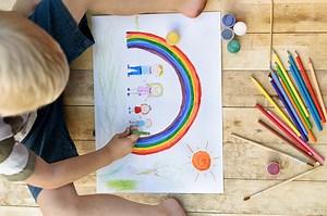 Netter Junge zieht Regenbogen und Familie. Open Air. Ansicht von...