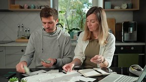 Couple managing home budget and counting money at kitchen table
