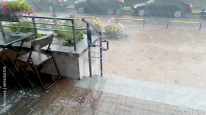 Rain, thunderstorm and hail on the porch of the house. Strong storm hurricane. Bad rainy weather in the city cafe