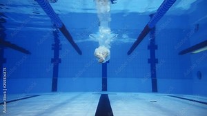 Muscular man under water in a swimming pool in super slow motion