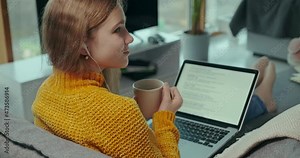 Internet education. Teenager student girl 11 years old studying at home using a laptop computer. She holds a cup of tea in her hand