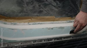 Repairing a car after an accident in a workshop garage. Cover the back of the body with white spackling paste. Professional auto Renovation.