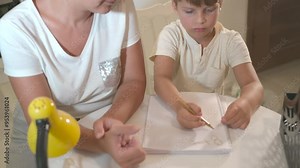mom helps son boy do homework for school the tutor helps the child to learn