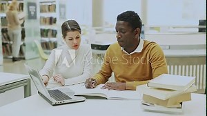 Two adult students studying together in public library