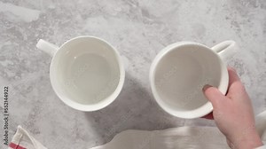 Flat lay. Step by step. Pouring chocolate cake batter into the cups to prepare chocolate mug cake.