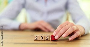Woman hand changes digit 3 to 4 from wooden cubes to form date as anticipation of starting of new year. Preparation for beginning of world holiday concept slow motion