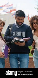 Group of diverse international students standing outdoors near the university building, discussing their lessons and assignments together while one student shows his notes in a textbook Stock Video Footage - Alamy
