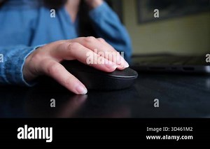Close-up of girl using computer mouse with laptop on desk, simple everyday home lifestyle moment