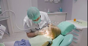 Male dentist drills the teeth of small child. Prevention of tooth decay.