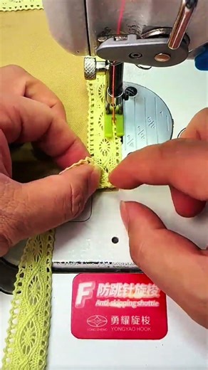 Hands guiding sewing machine to attach yellow lace trim