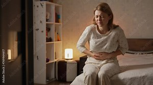 Woman suffering from stomach ache sitting on toilet, holding belly, feeling abdominal or menstrual pain. Gastritis, diarrhea and painful periods concept