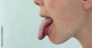 Close up of woman showing tongue side view. Girl with her tongue out on a blue background
