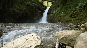 A waterfall falls from a cliff in the jungle among the green vegetation. spring melting of glaciers