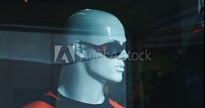 The interior of a men's clothing store for sports. Male mannequins in swimming suits behind transparent glass. Men's diving glasses. Goods for sports in the window, men's clothing store in department