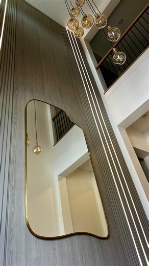 Not Just Wall – Bespoke Media Walls & Cabinetry on Instagram: "This project is a perfect example of how a wall becomes a statement, not just a surface. A two-story feature wall combining slat panels and flat panels creates depth and architectural rhythm. Six integrated LED light strips enhance the vertical lines and add a premium ambient glow. We designed and built a custom shoe cabinet in the same finish to keep the space visually seamless, then completed the project with a carefully selected c