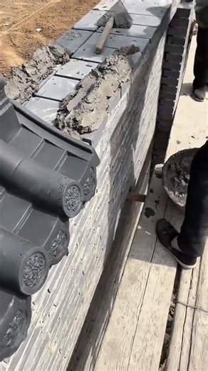 installing black traditional roof tiles on top of a wall to provide protection and decoration