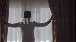 Man Open Big Window Curtains.Man In Dark Room Opens Curtains Slow Motion.Man Unveil Curtains And Admire Garden View From Window In Slow Motion.Man Looking At Window Slow Motion.Guy Stay Against Window
